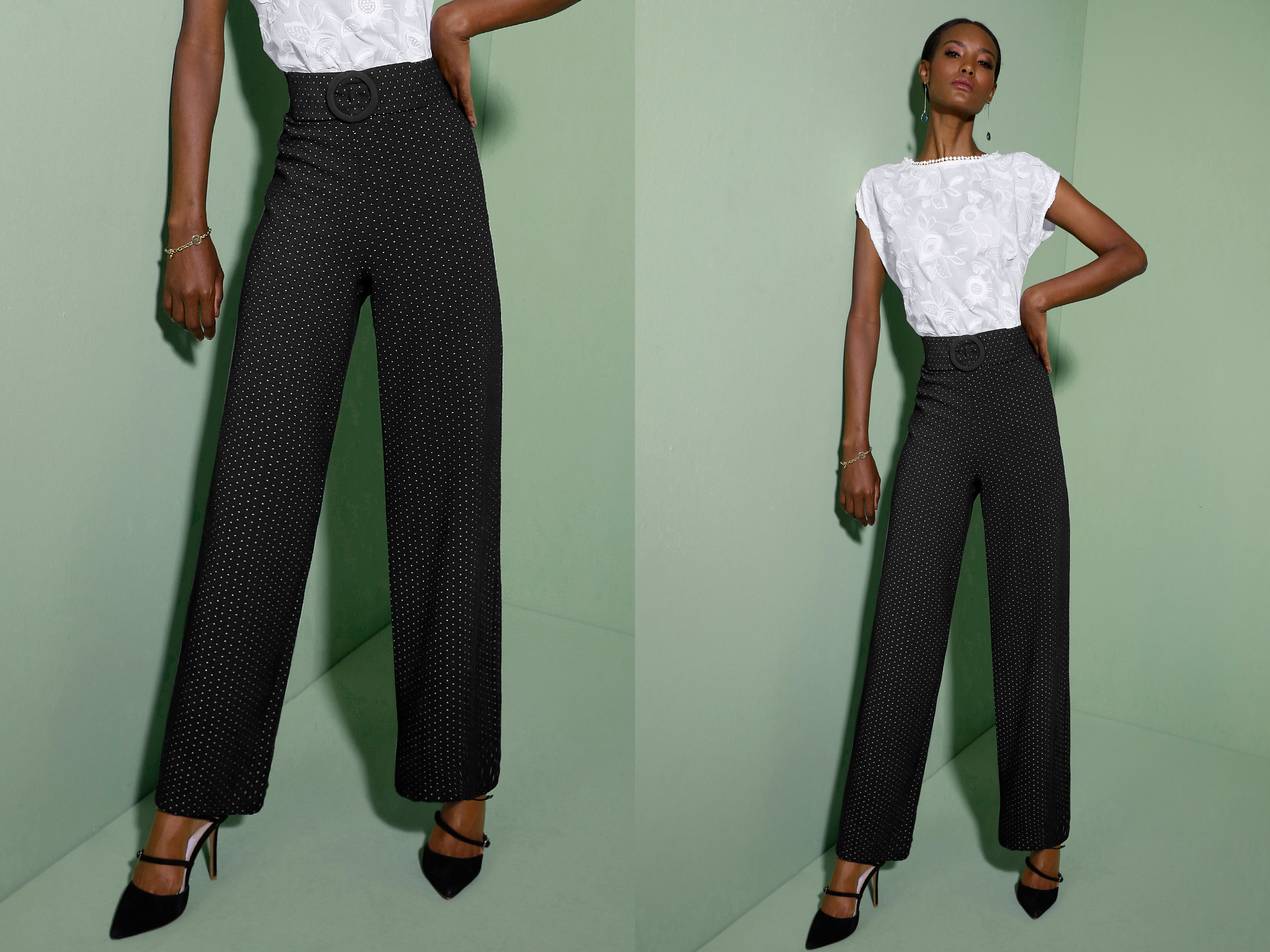 Schwarze, weit geschnittene Hose mit weißen Punkten und hoher Taille, kombiniert mit weißem Oberteil mit floralen Stickereien, getragen mit schwarzen Absatzschuhen vor grünem Hintergrund.