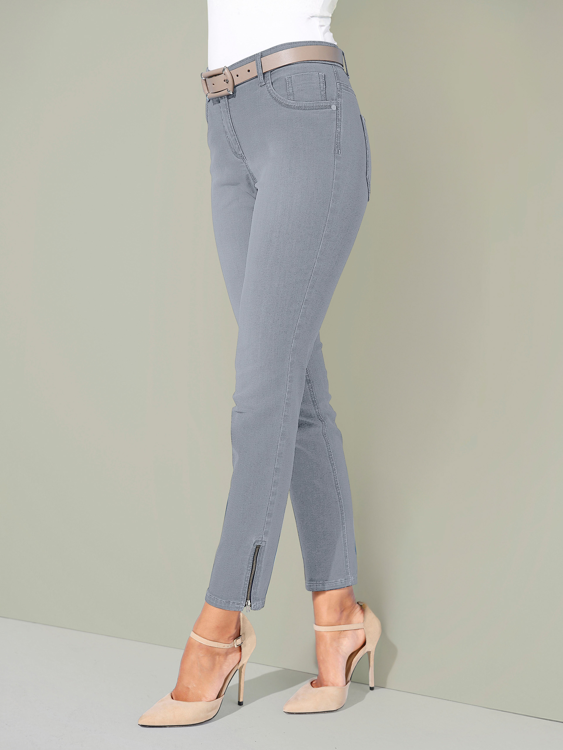 Beine von einem Model mit grauer Hose steht vor grünem Hintergrund.