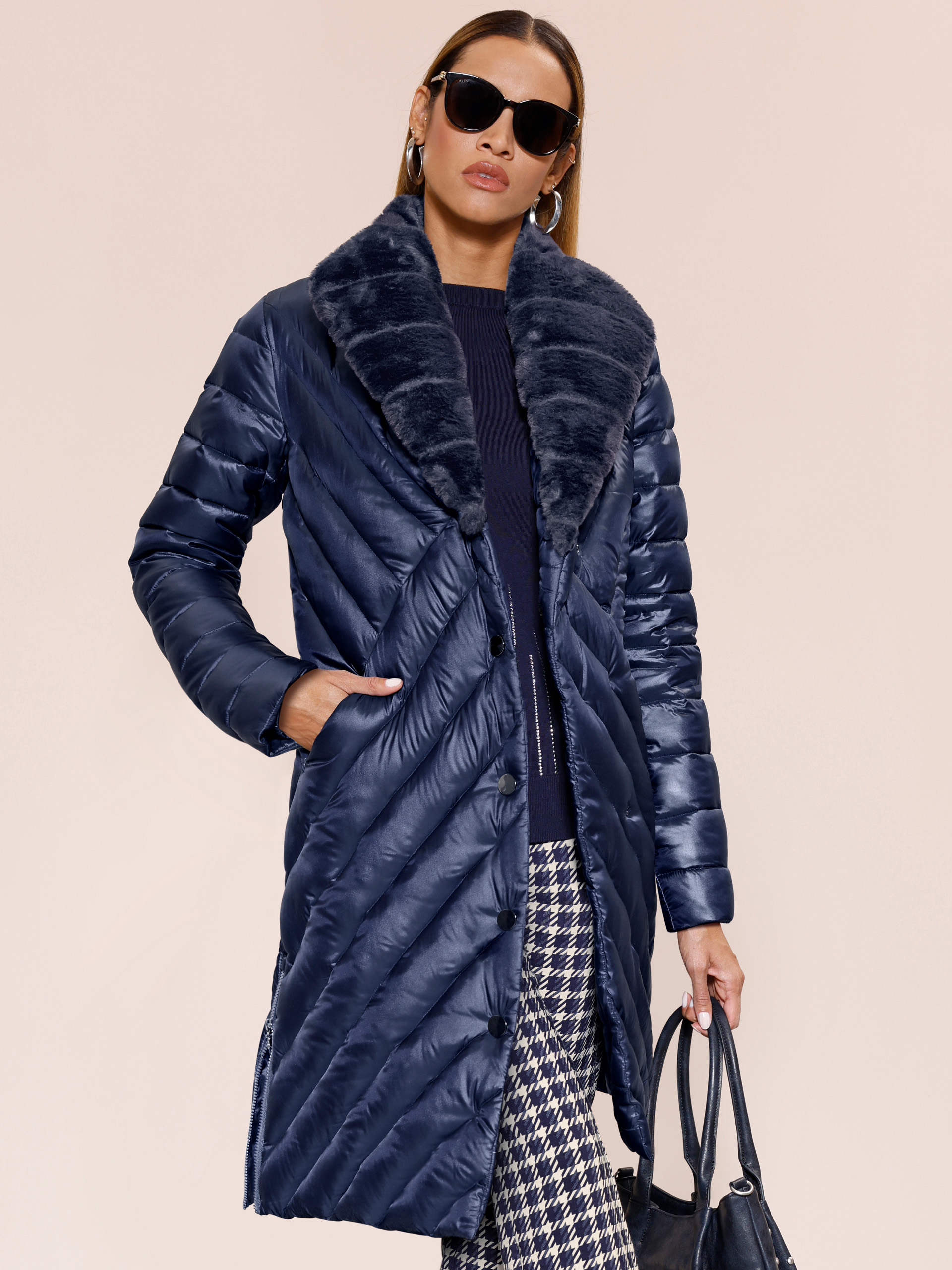 Ein Model trägt eine türkisfarbene Steppjacke mit Kapuze, das andere Model einen dunkelblauen, langen Steppmantel mit großem Kragen.