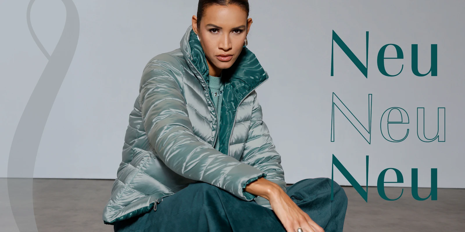 Ein Model sitzt auf dem Boden und trägt eine glänzende, silberne Steppjacke mit grünem Innenfutter. Rechts steht mehrfach das Wort 'Neu'.