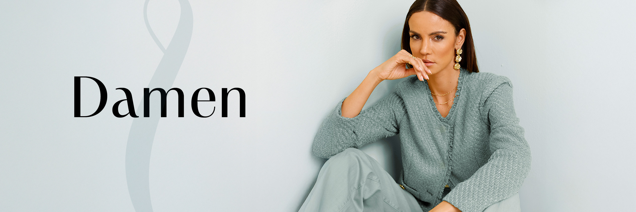 Model sitzt vor türkisfarbenem Hintergrund. Rechts daneben steht das Wort Damen.