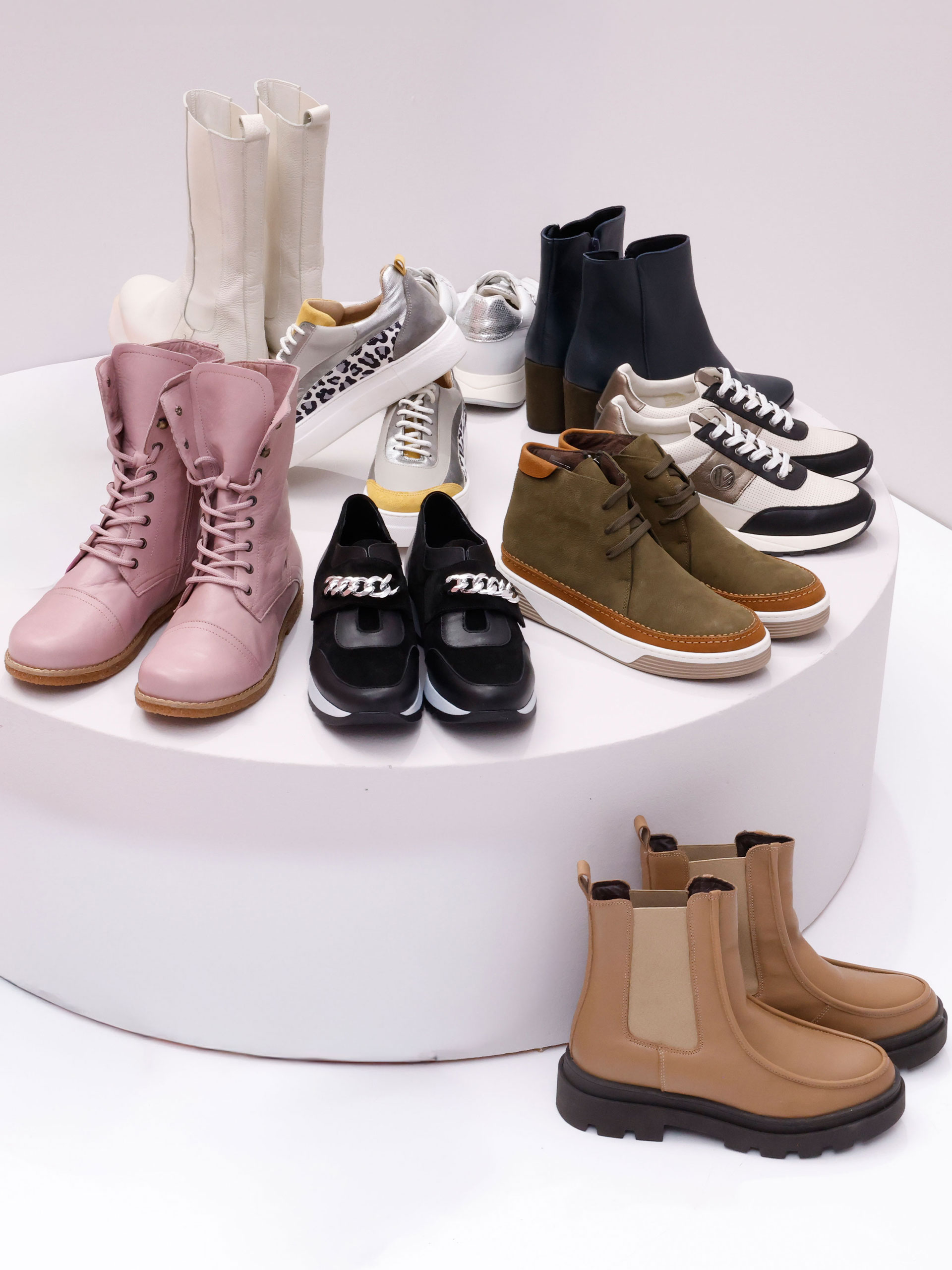 Ein Model trägt graue, gelbe und silberne Sneaker mit Leopardenmuster an den Seiten, dazu schwarze Lederhosen.