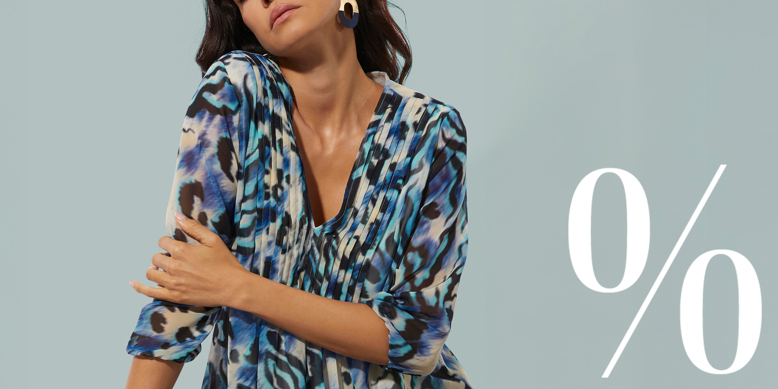 Model mit Bluse vor türkisfarbenem Hintergrund mit Prozentzeichen