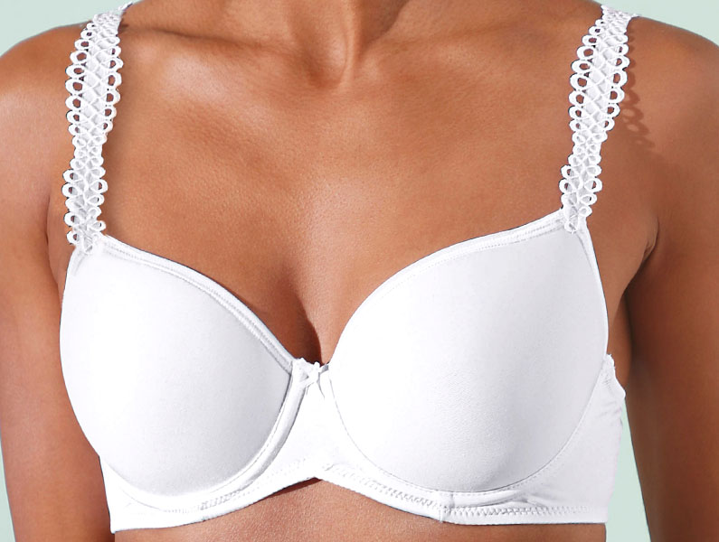 Weißer BH mit dekorativen Trägern, getragen von einer Person vor hellem Hintergrund.