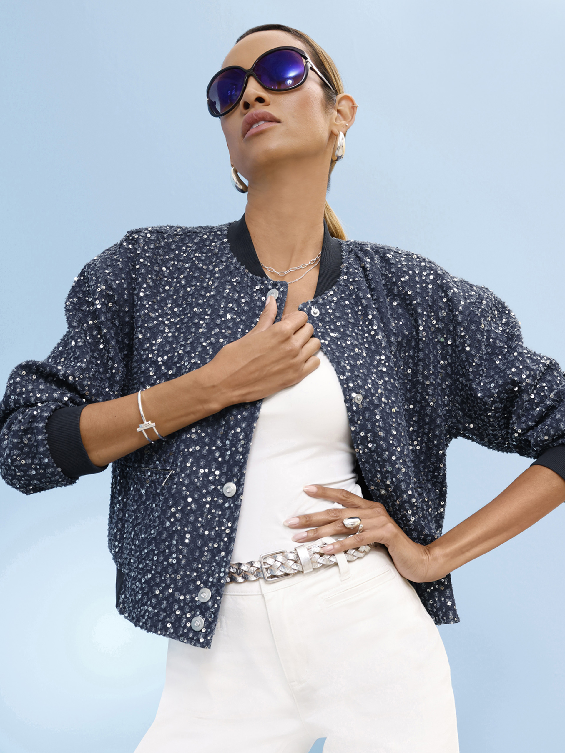 Ein Model mit blauer Jacke und weißer Hose steht vor hellblauem Hintergrund. Es steht dreimal das Wort 'Neu' in grauer Schrift.