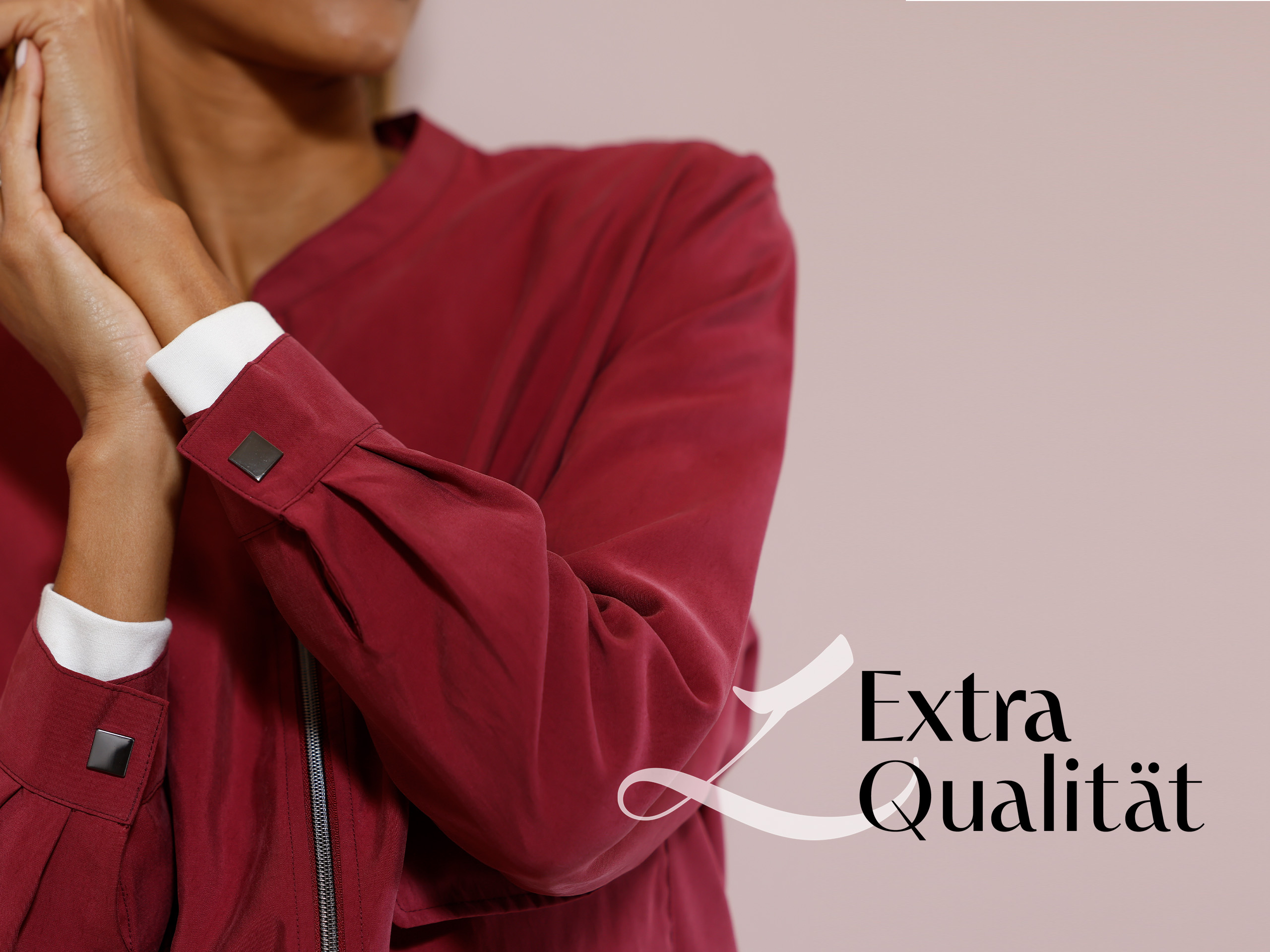 Ein Model trägt eine bordeauxrote Jacke mit weißen Manschetten, der Schriftzug 'Extra Qualität' ist rechts unten zu sehen.