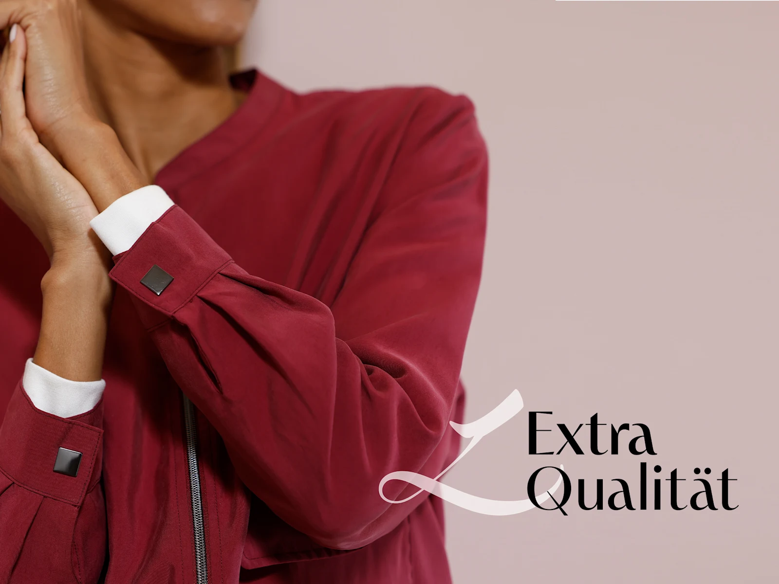 Ein Model trägt eine bordeauxrote Jacke mit weißen Manschetten, der Schriftzug 'Extra Qualität' ist rechts unten zu sehen.