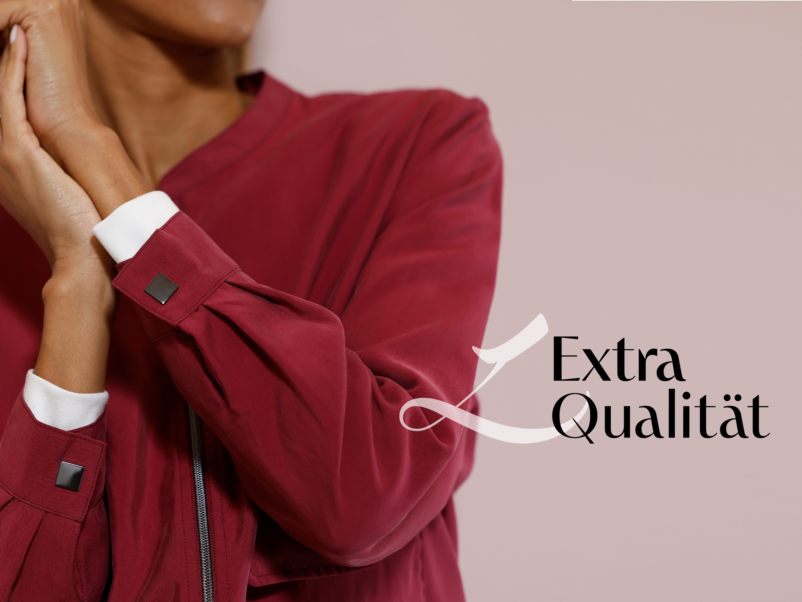 Ein Model trägt eine bordeauxrote Jacke mit weißen Manschetten, der Schriftzug 'Extra Qualität' ist rechts unten zu sehen.