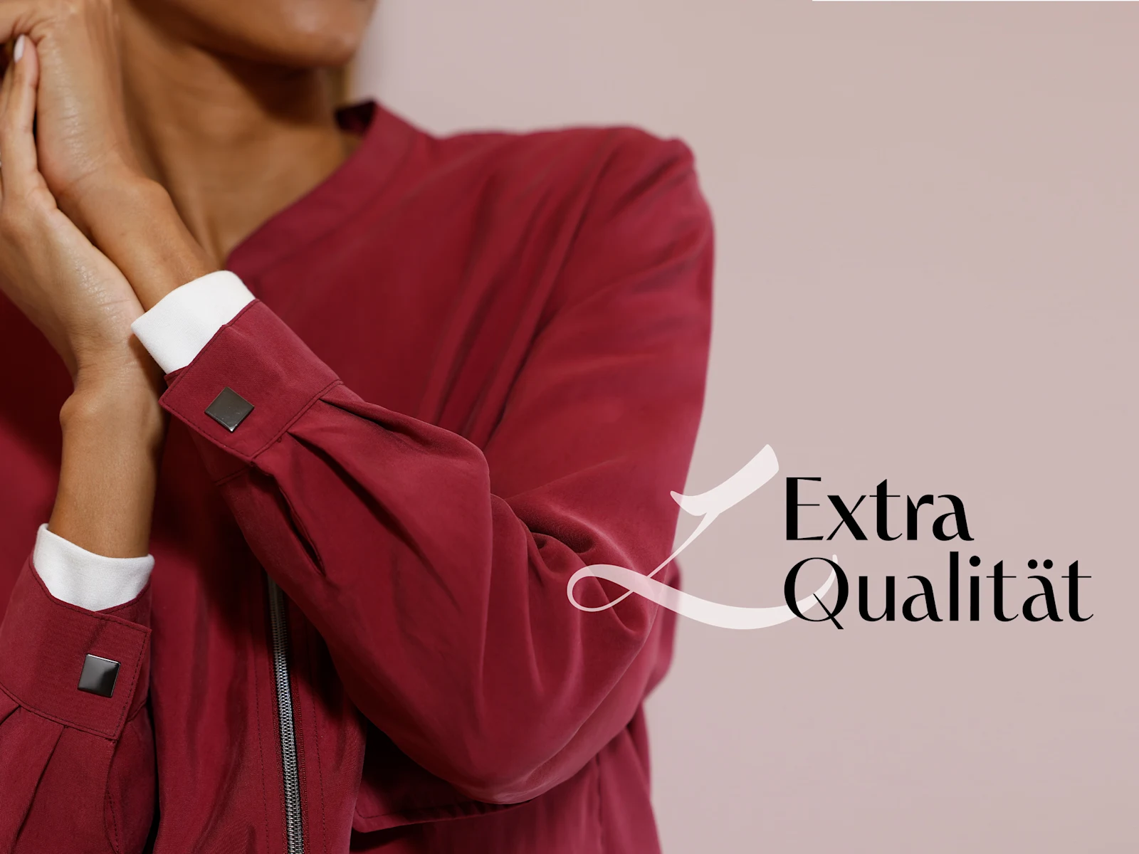 Ein Model trägt eine bordeauxrote Jacke mit weißen Manschetten, der Schriftzug 'Extra Qualität' ist rechts unten zu sehen.