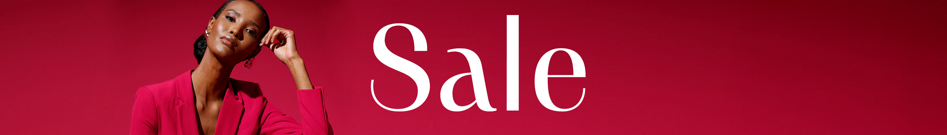 Ein Model sitzt in einem roten Anzug vor rotem Hintergrund, daneben steht groß das Wort 'Sale' in weißer Schrift.
