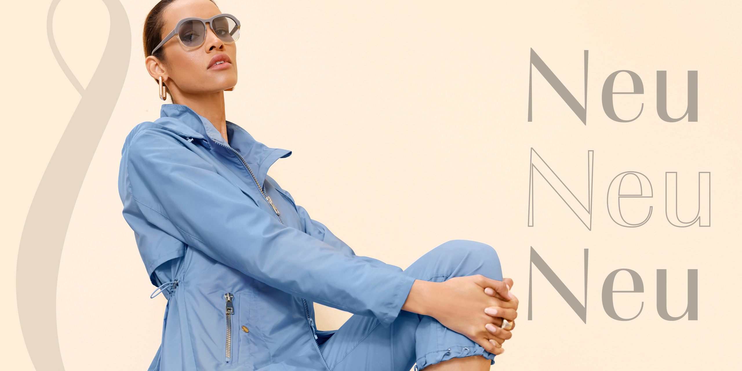 Das Bild zeigt eine Frau, die eine hellblaue Freizeitjacke und passende Hosen trägt. Sie sitzt auf einer hellbeigen Fläche und trägt eine Sonnenbrille. Auf dem Bildes steht dreimal das Wort "Neu" in verschiedenen Grautönen und Schriftstilen.