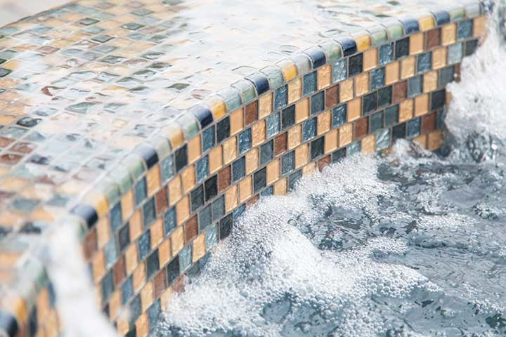 A close up of a waterfall in a pool with bubbles coming out of it .