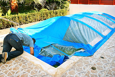 man-cleaning-pool-under-winter-cover