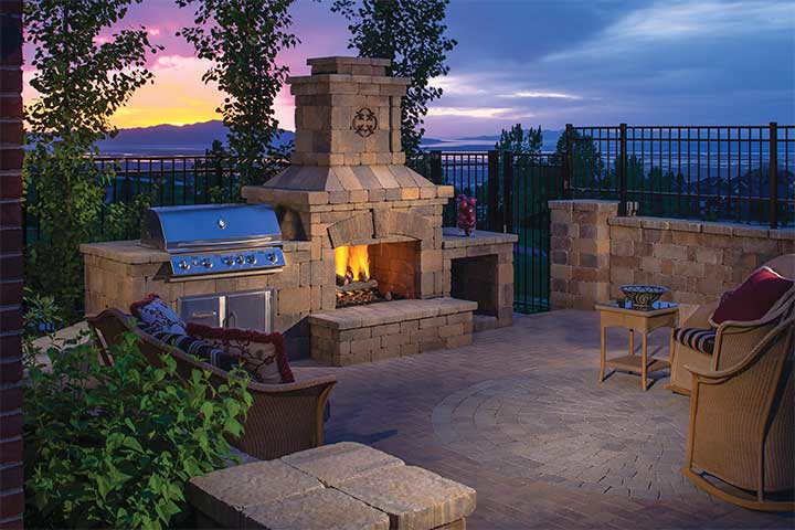 A patio with a fireplace and a grill at sunset