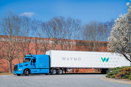 A blue, Waymo Via truck with the 4th-gen Waymo Driver and branded trailer