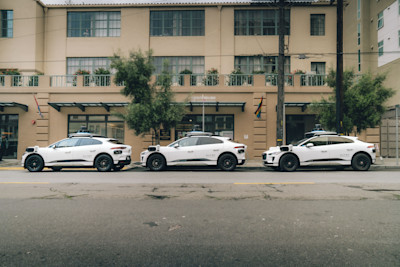 Three Waymo vehicles parked outside of Openhouse before heading out to deliver groceries to community members.