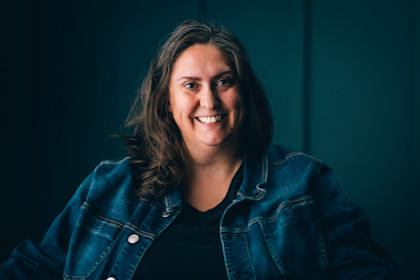 Portrait of Christy Moore, the founder of Social Spin. She has shoulder length brown hair and is wearing a denim jacket.