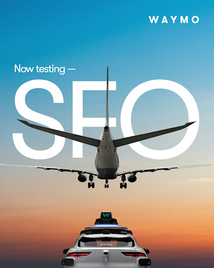 A plane flying over a Waymo vehicle. 