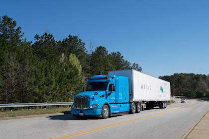 A blue, Waymo Via truck on a freeway