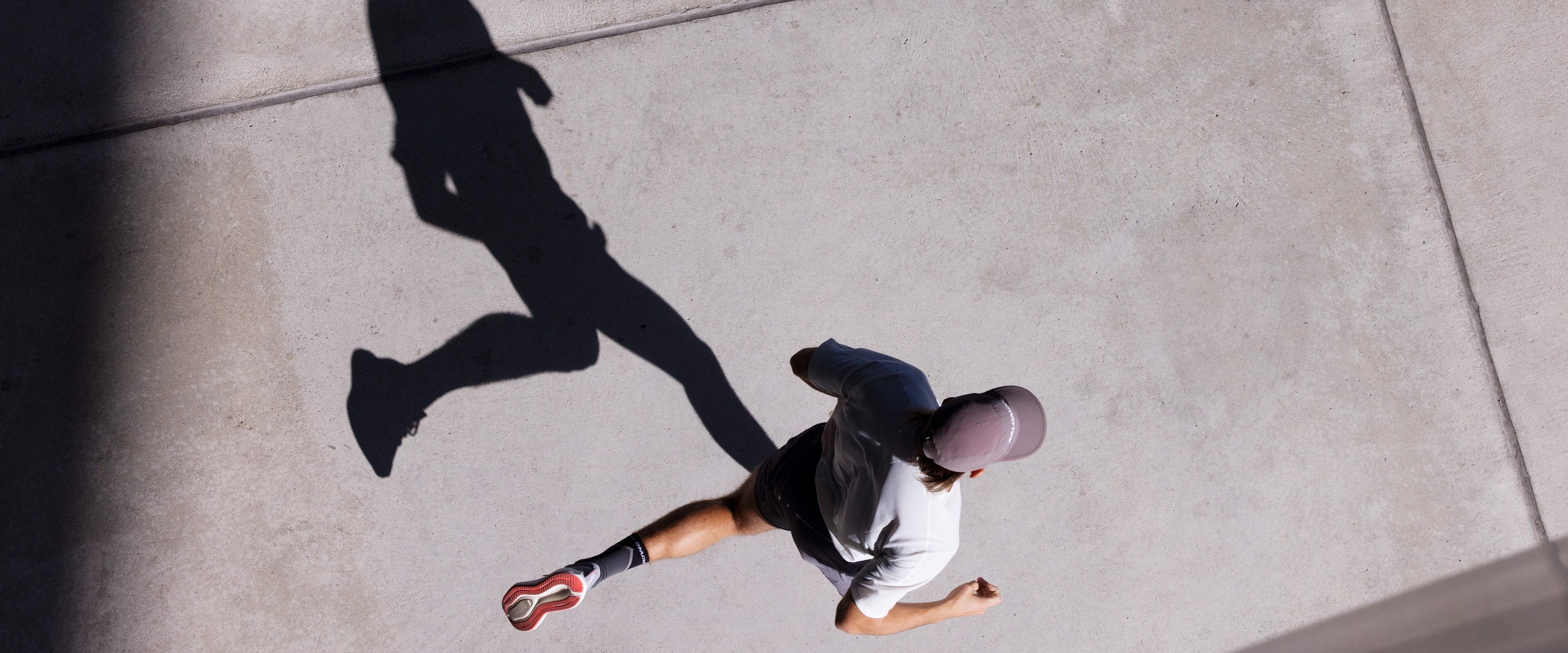 Overhead view of a runner in a city with his shadow clearly defined showing his strides