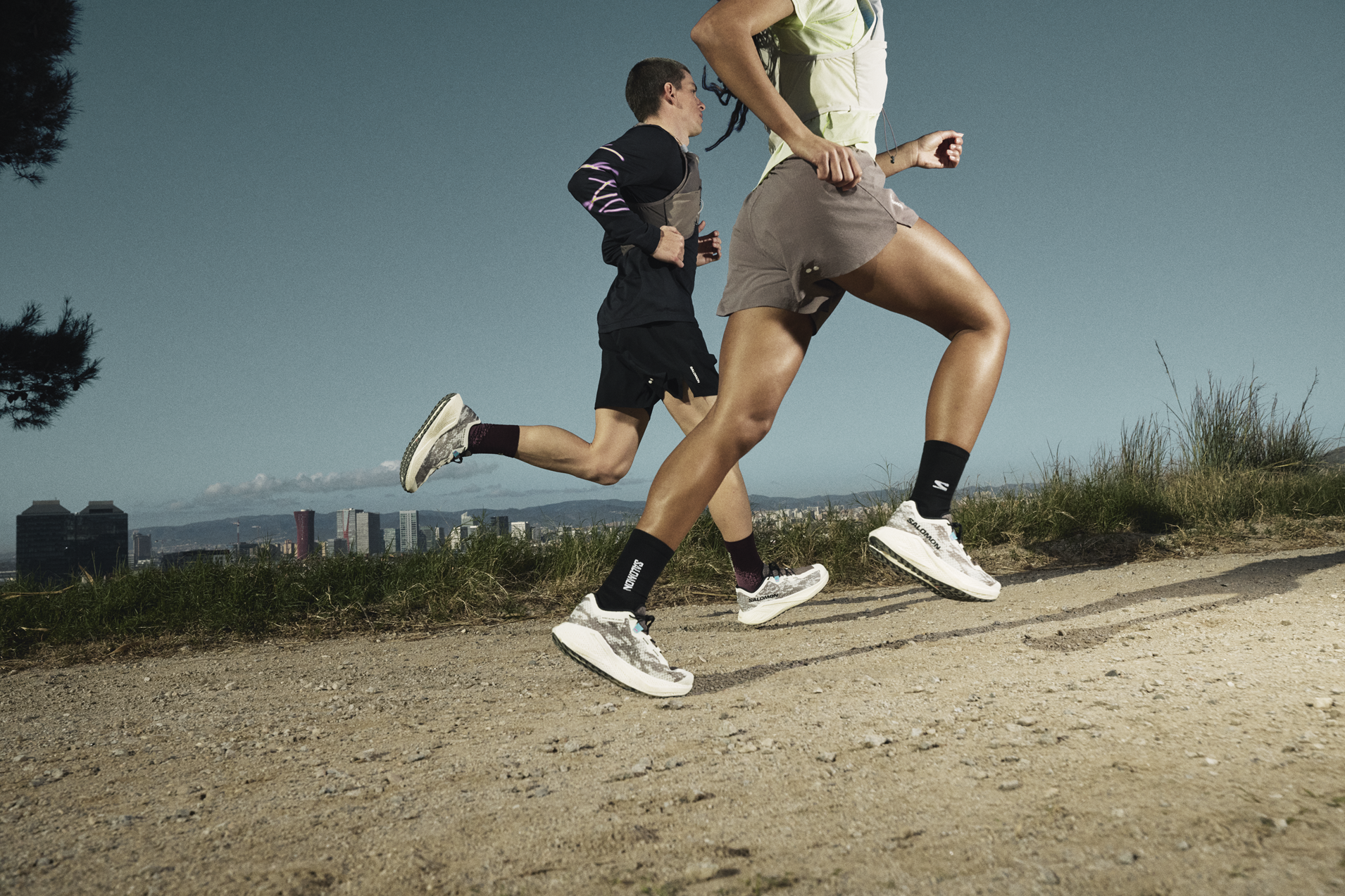 Deux coureurs sur un large chemin de gravel running avec vue sur la ville.