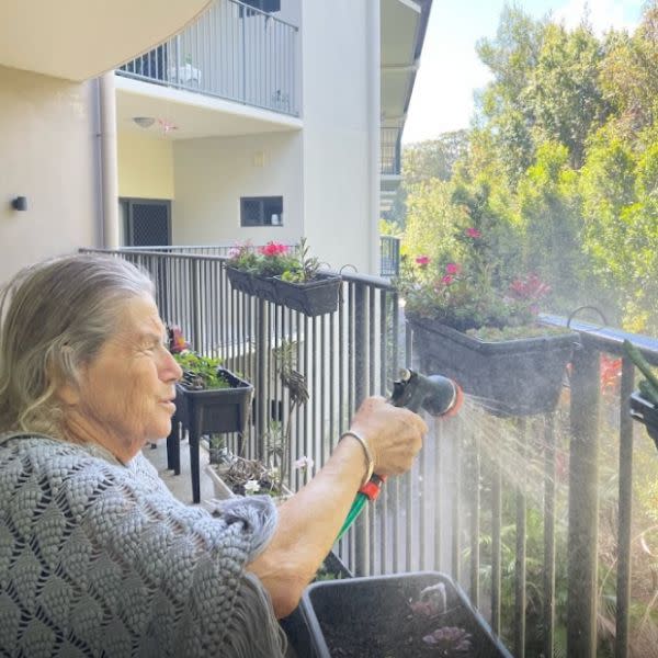 Bupa Tugun aged care elderly resident watering plants at care home balcony