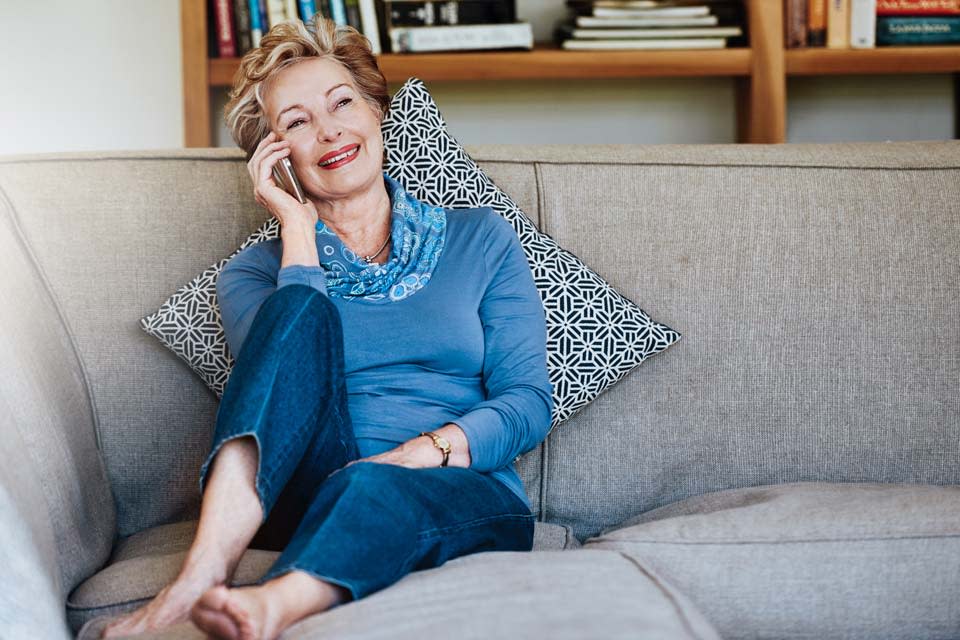 Mature lady sitting on lounge talking on her mobile phone