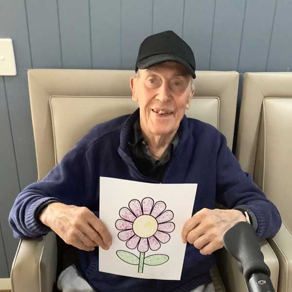Doug from secure dementia support community creating flower art smiling