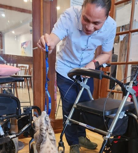 Bupa Enfield’s lifestyle coordinator Raj using their lanyard to play with a cat