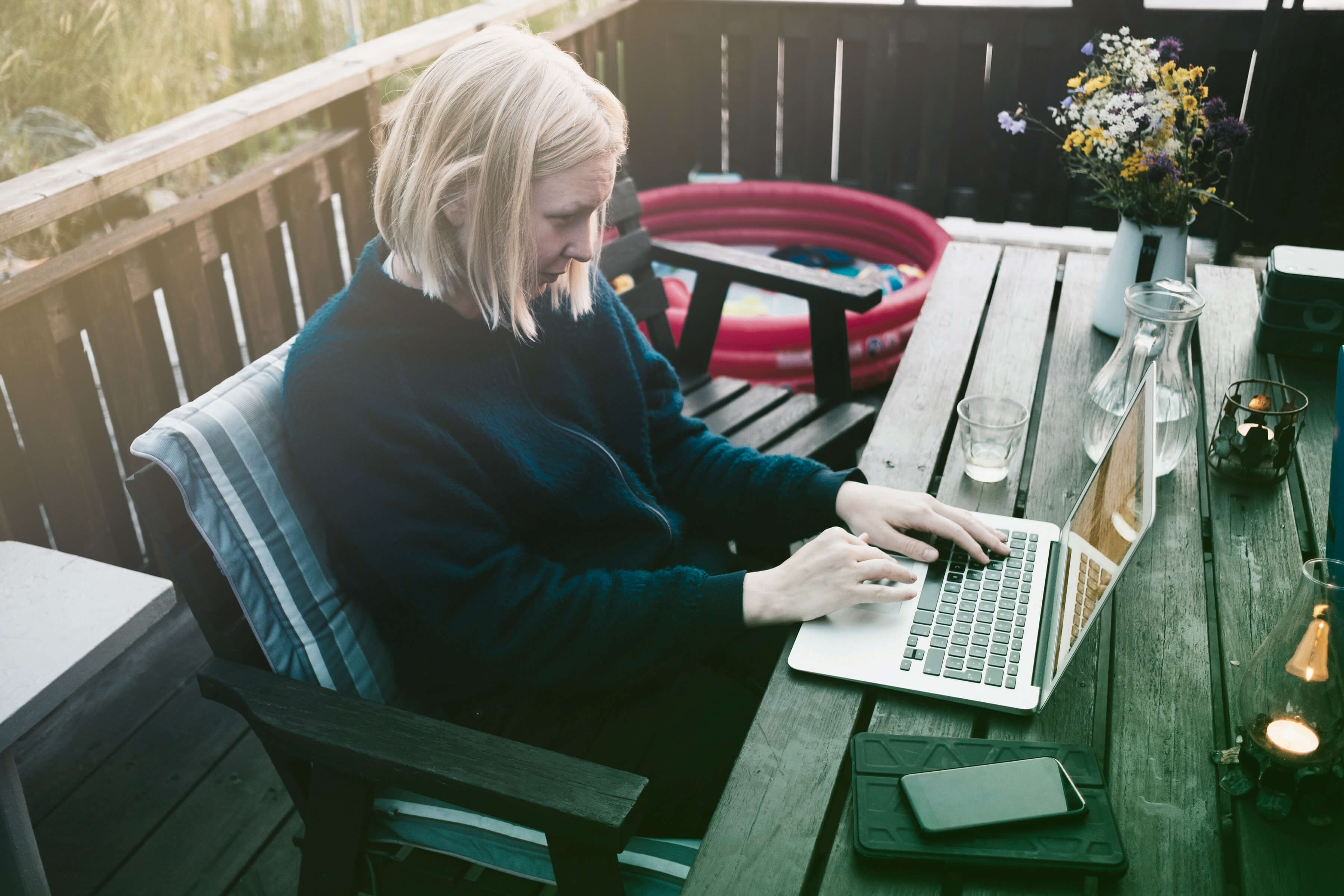 Kvinna sitter på en uteplats och jobbar på sin dator. 