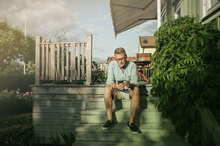 A man is sitting on a staircase and looking at his mobile.