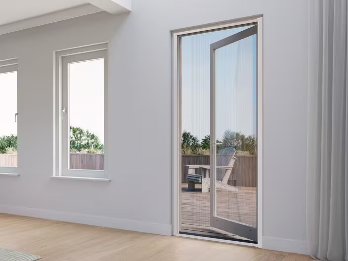 Moderne kamer met enkele deur met hor die uitkijkt op een terras met tuinmeubelen en groene omgeving.