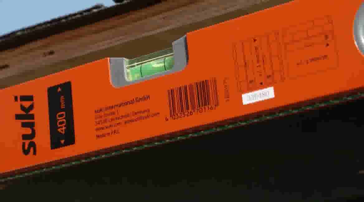 Oranje waterpas van Suki (400 mm) met groene luchtbel, gebruikt op een houten oppervlak voor nauwkeurige nivellering.