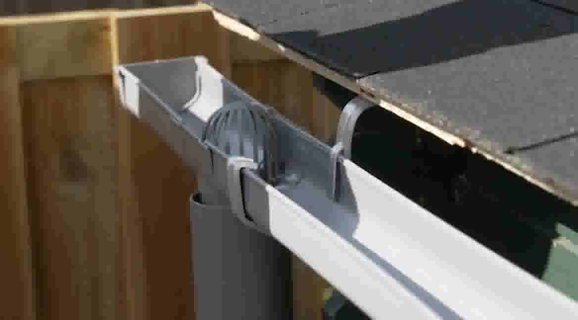 Uitschuifbare goot met regenwaterafvoer gemonteerd aan dakrand, verbonden met een grijze afvoerpijp.