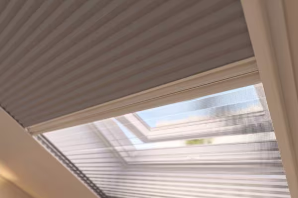 Lichte zolderkamer met dakraam en raamhor, witte bureau met lamp en minimalistische houten planken aan de muur.