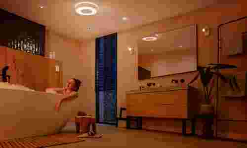 Persoon ontspant in een luxe badkamer met warme verlichting van Philips Hue