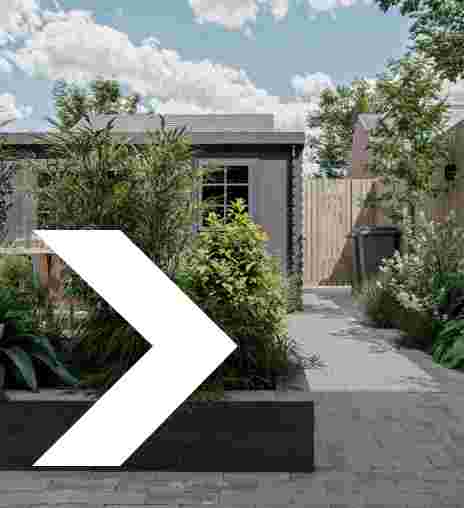 Groene tuin met diverse planten, een houten schutting en een grijze afvalcontainer naast een huis met raam.