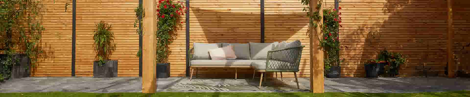 Loungeset onder pergola met schaduwdoek