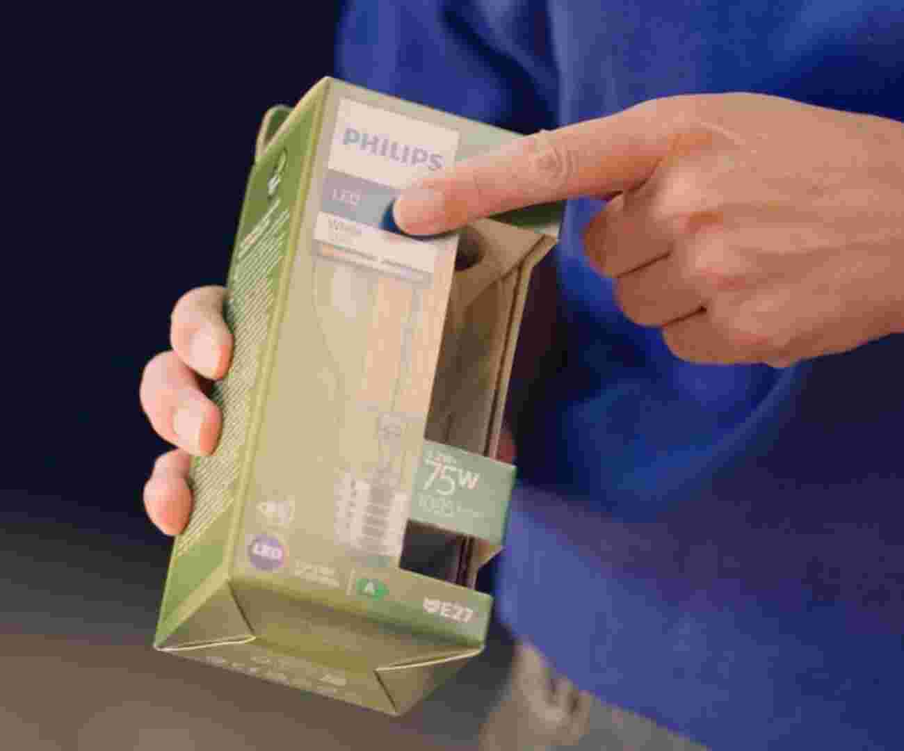 Iemand in een blauwe GAMMA trui houdt een verpakking van een Philips LED-lamp vast en wijst daarbij naar het aantal kelvin (kleurtempratuur)
