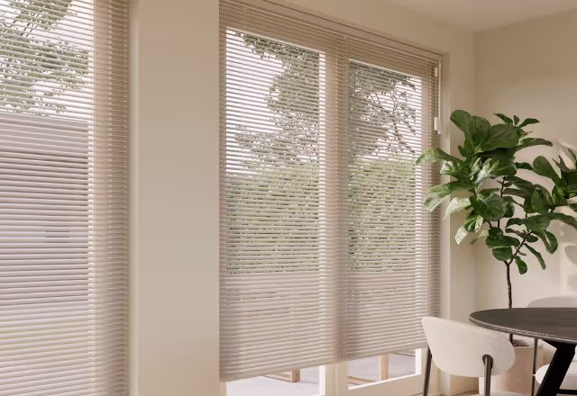 Beige jaloezieën voor grote ramen in een modern, licht interieur met een groene kamerplant.