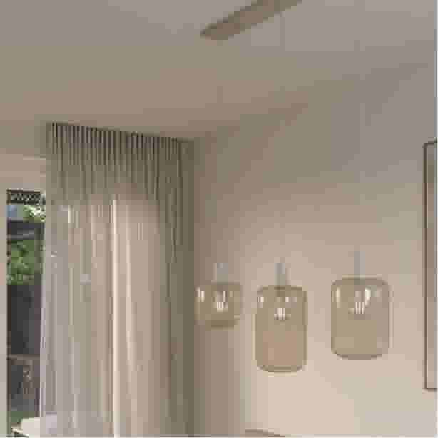 Hanglamp met drie amberkleurige glazen bollen aan een plafondplaat, boven een lichte woonkamer