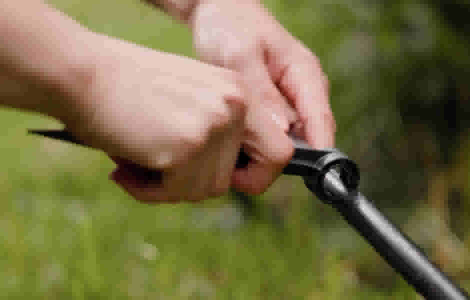 Handen stellen een zwarte tuinslang of irrigatiebuis af tegen een groene achtergrond van gras in een tuin.