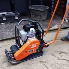 Oranje gehuurde trilplaat van RentPartner Boels op zandgrond met gereedschapskist en emmer op de achtergrond.