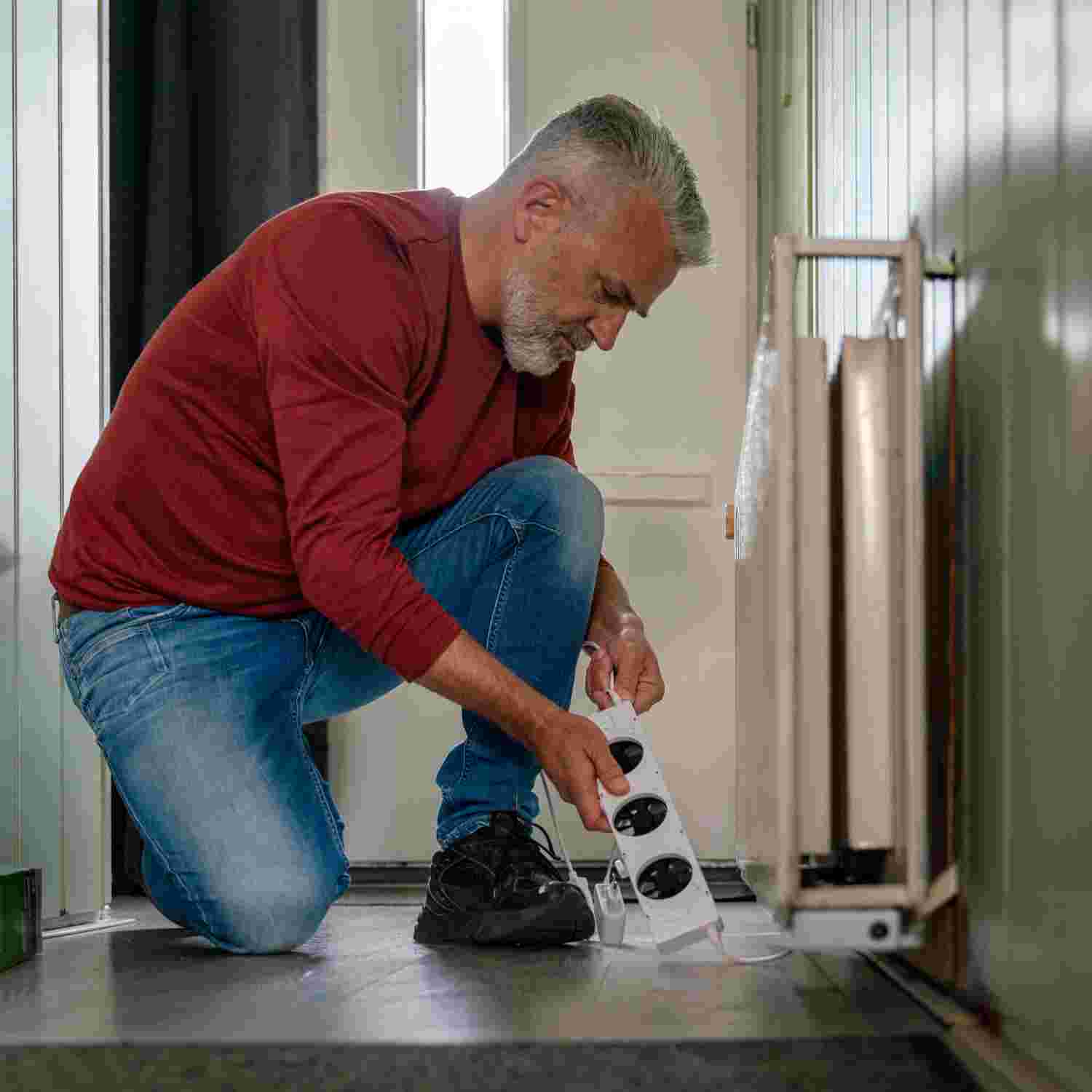 Man installeert een radiatorventilator onder zijn radiator