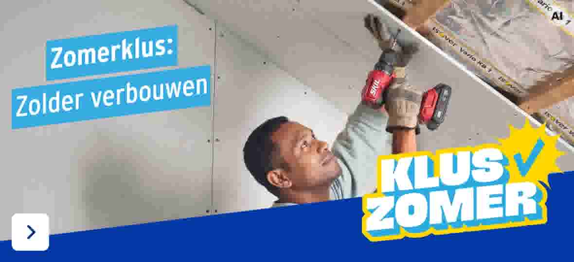 Man schroeft gipsplaten aan het plafond met een rode accuboormachine tijdens een zolderverbouwing.