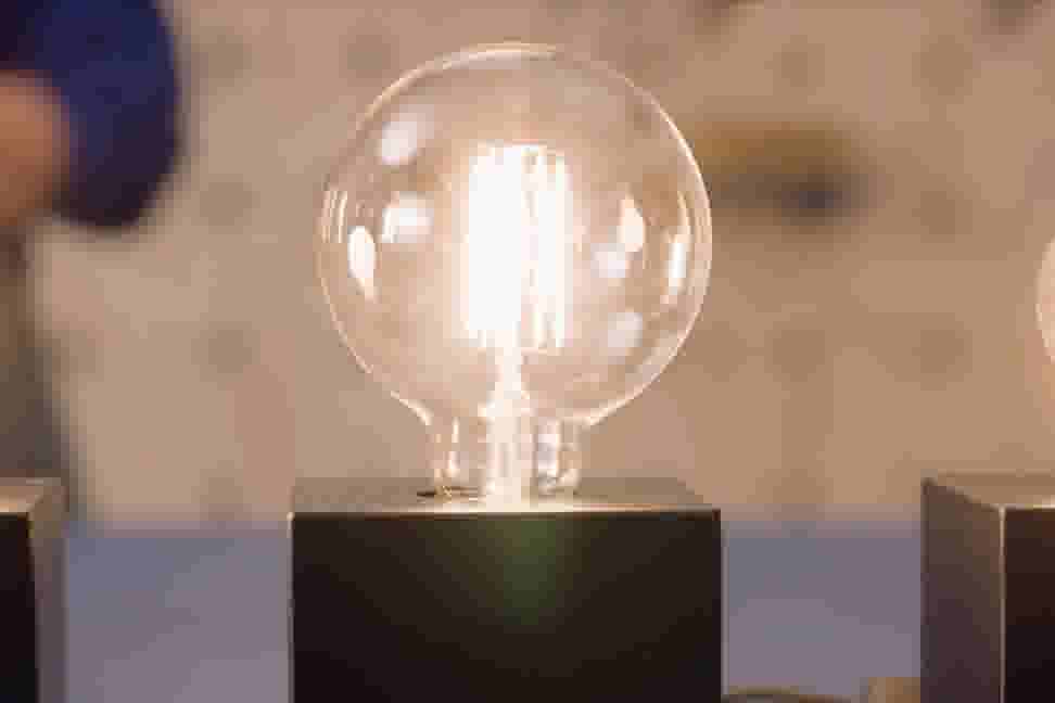 Een brandende LED lamp met globe vorm tegen een onscherpe achtergrond.