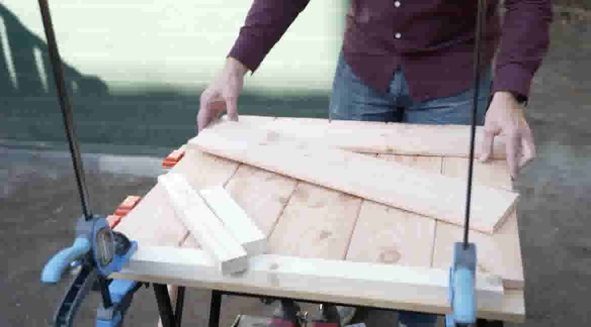 GAMMA klusser plaatst houten planken op een werkbank met klemmen voor een doe-het-zelf project.