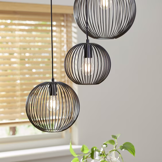 Drie hanglampen met bolvormige metalen kappen boven een vensterbank.