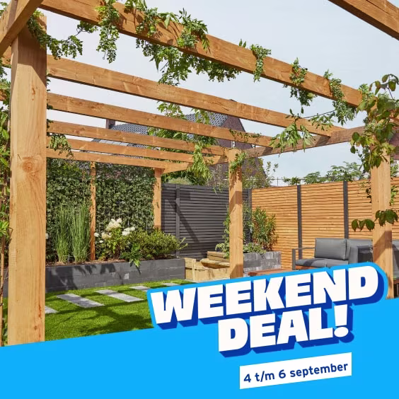 Achtertuin met een houten pergola, groene beplanting en een zwarte schutting, met op de voorgrond een stapel houten planken. Weekenddeal van 4 t/m 6 september