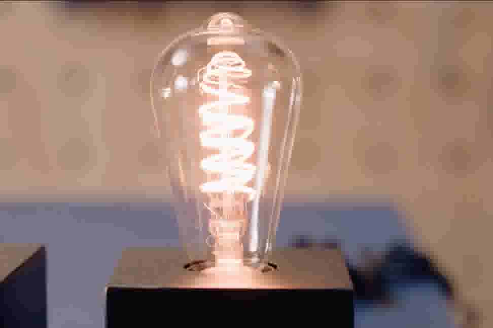 Een brandende LED lamp met Edison vorm tegen een onscherpe achtergrond.